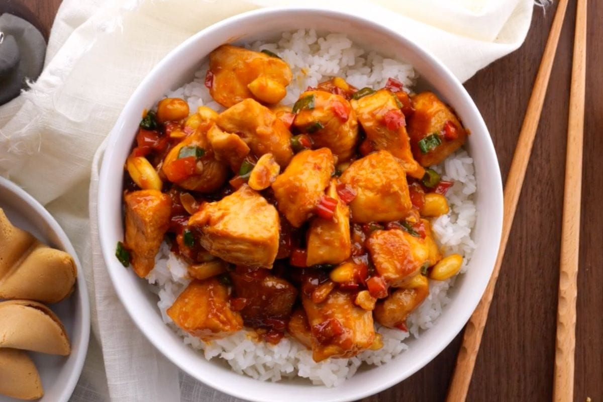 Kung Pao Chicken over rice in bowl with chop sticks