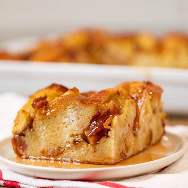 Square of Maple Bacon French Toast Bake on white plate with maple syrup