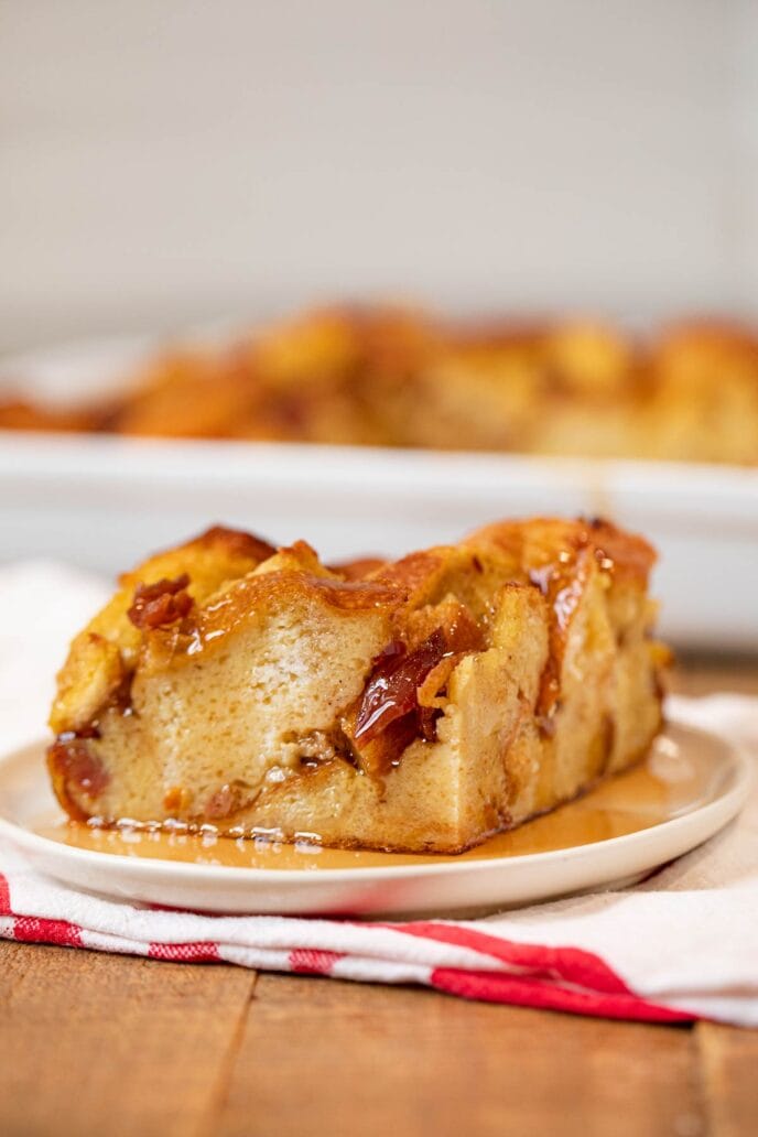 Square of Maple Bacon French Toast Bake on white plate with maple syrup