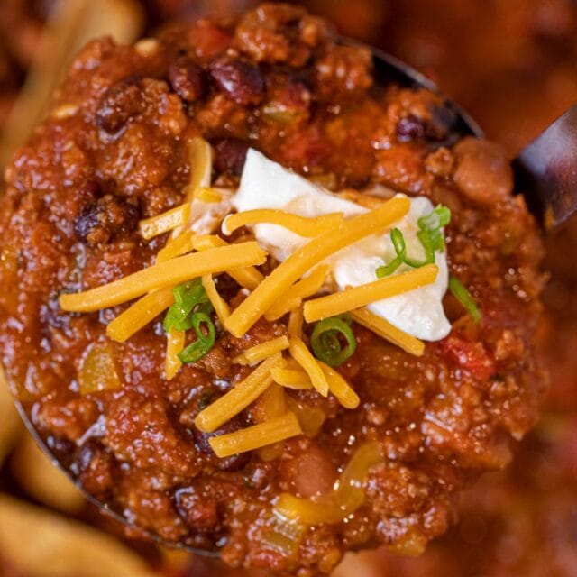 Ladle of chili topped with shredded cheese