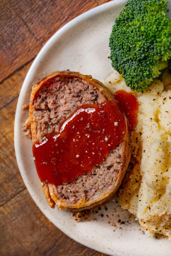 Bacon-Wrapped Meatloaf slice on plate with mashed potatoes and broccoli