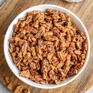 Candied Pecans in serving bowl on wood round