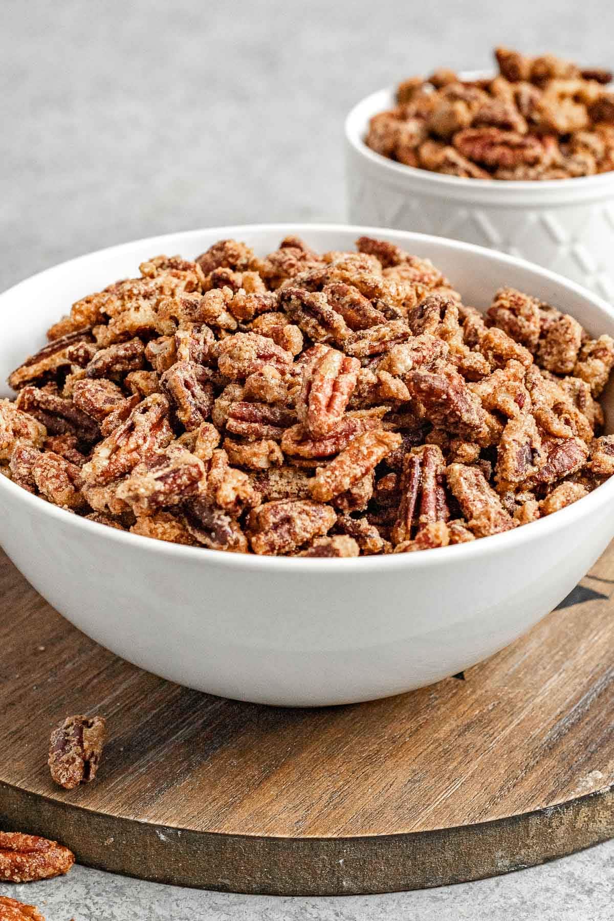 Candied Pecans in serving bowl on wood round