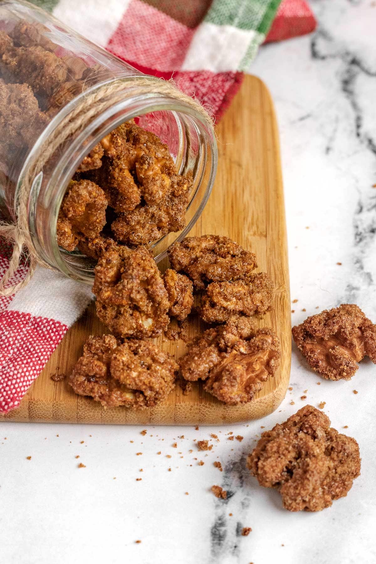 Candied Walnuts in a jar tipped over on cutting board