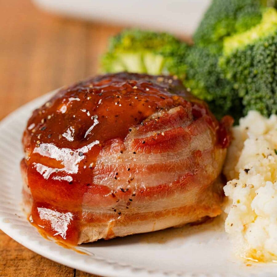 Individual Bacon Wrapped Meatloaf on plate with mashed potatoes and broccoli