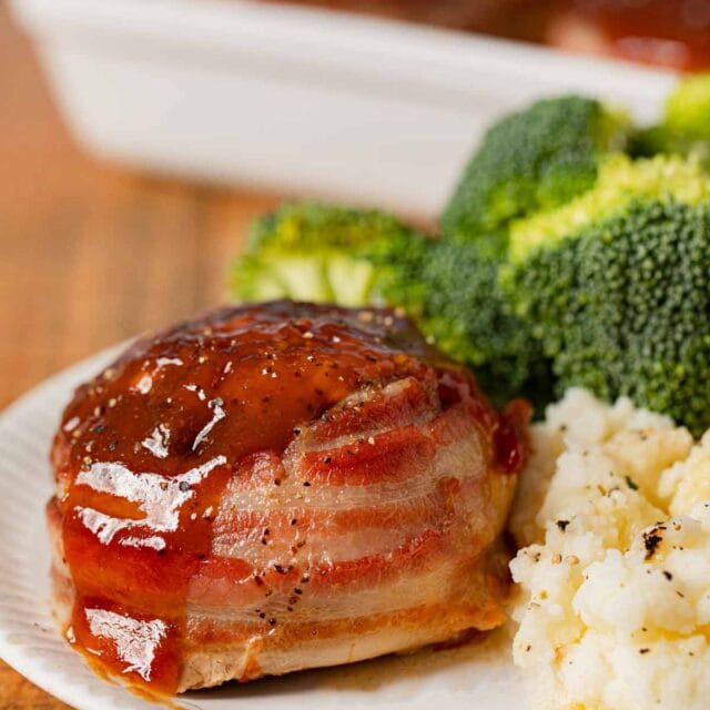 Individual Bacon Wrapped Meatloaf on plate with mashed potatoes and broccoli