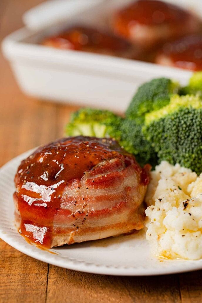 Individual Bacon Wrapped Meatloaf on plate with mashed potatoes and broccoli