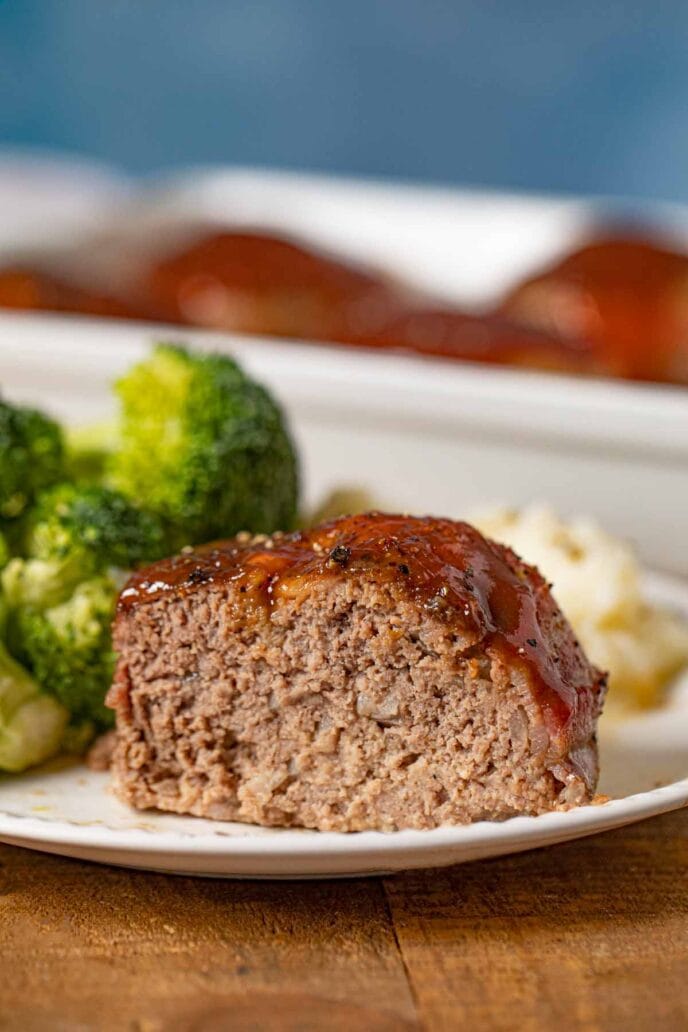 Individual Bacon Wrapped Meatloaf on plate with mashed potatoes and broccoli