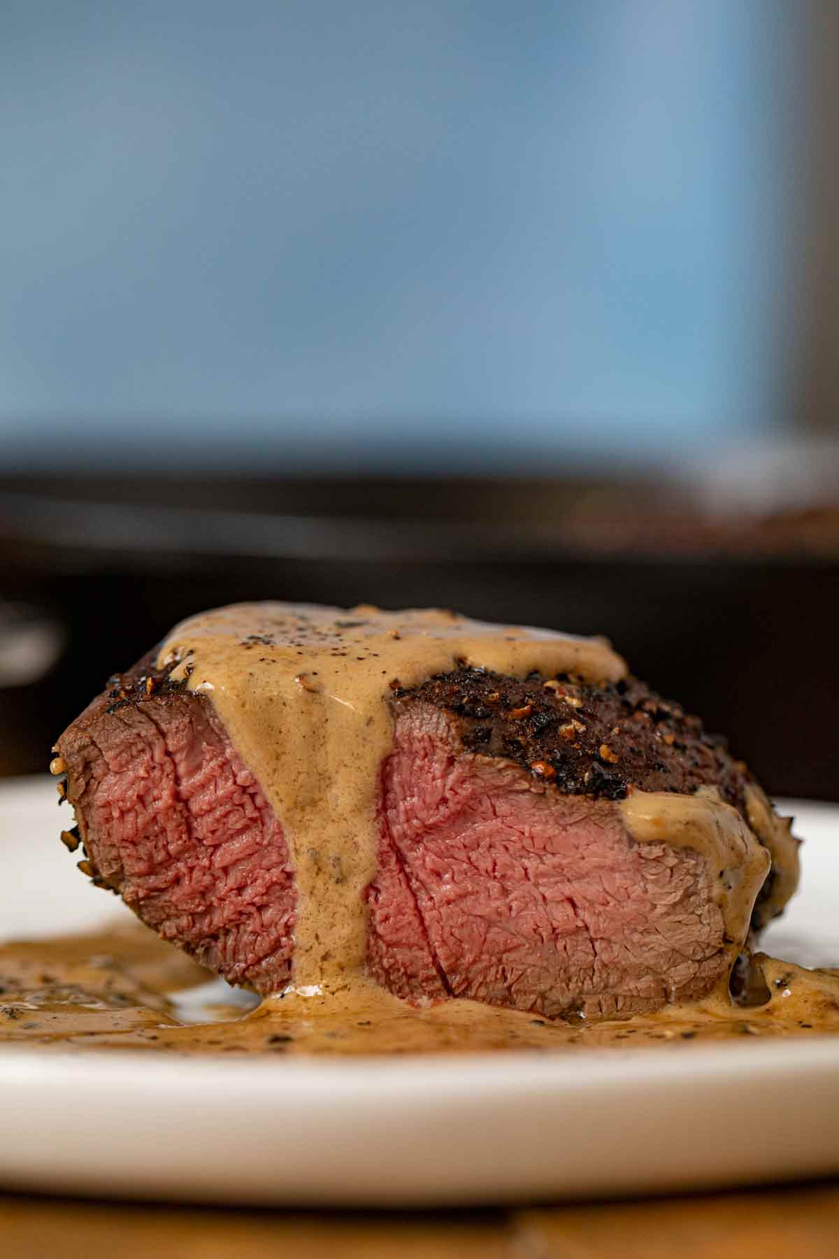 Steak Au Poivre sliced open on plate with pepper sauce