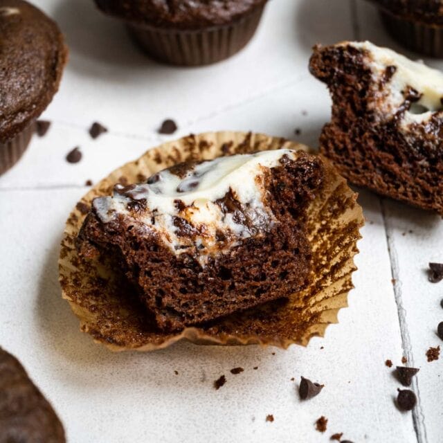 Black Bottom Cupcakes on counter with chocolate chips cut in half to see filling