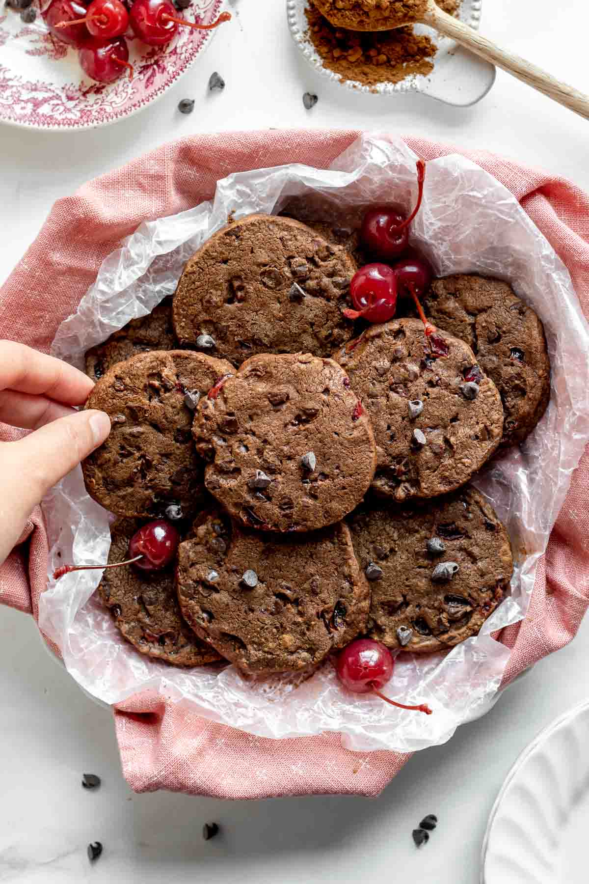 Cherry Chocolate Shortbread Cookies pile of cookies in a basket with hand removing cookie