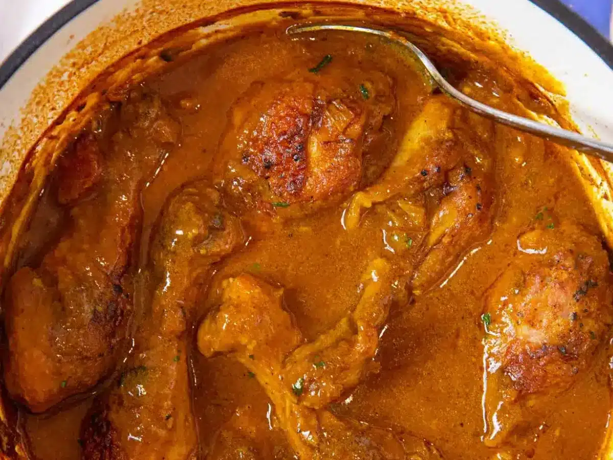 Close up of chicken legs in pot with spoon