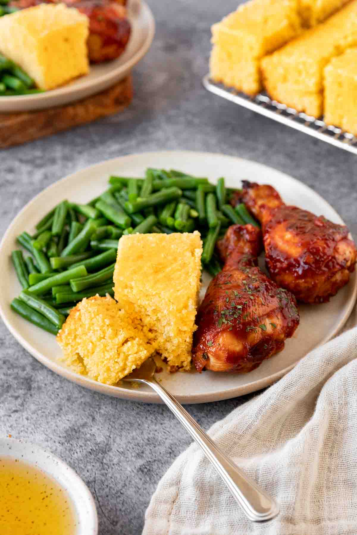 Honey Cornbread slice on plate with chicken and green beans