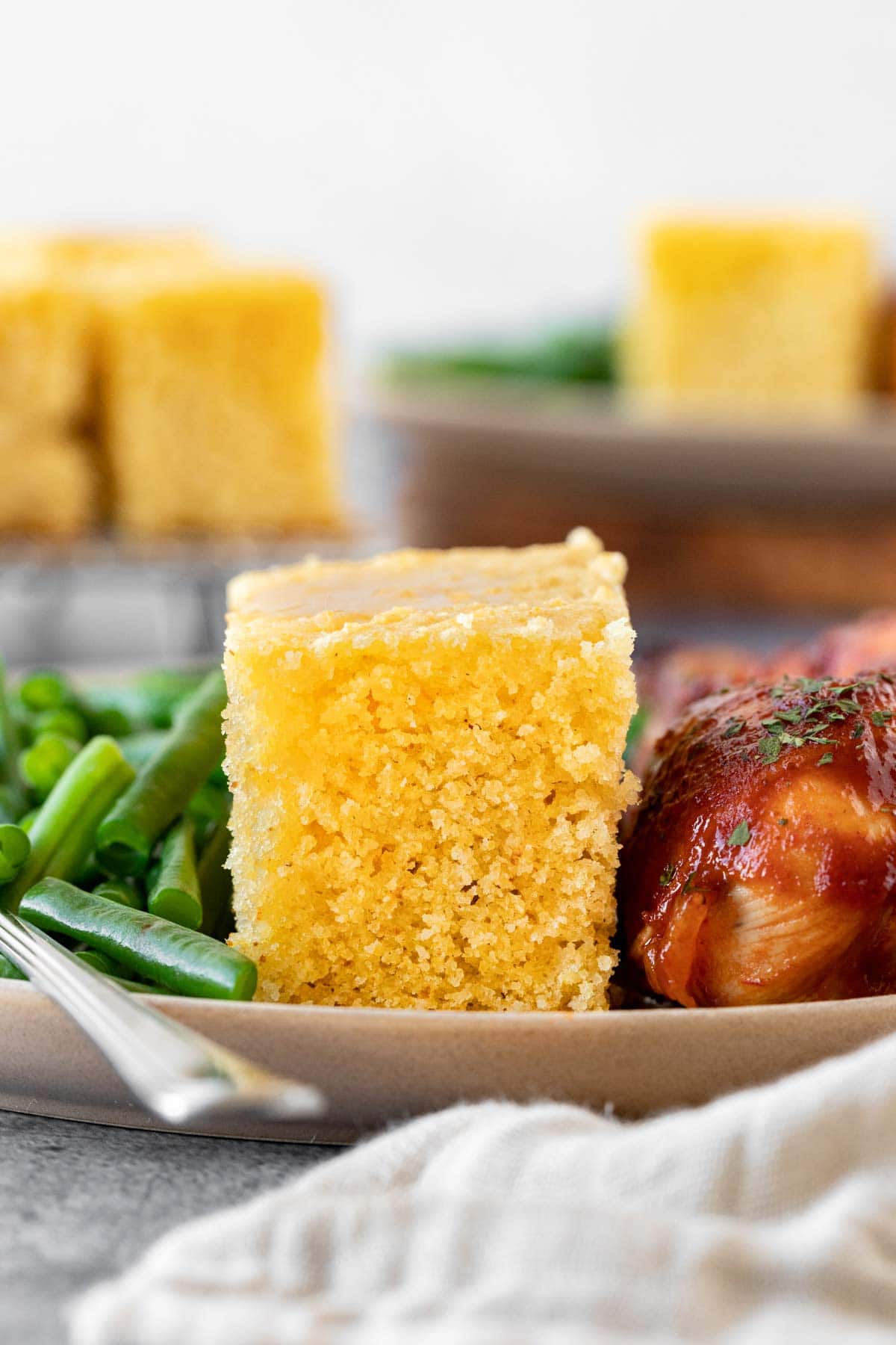 Honey Cornbread slice on plate with chicken and green beans