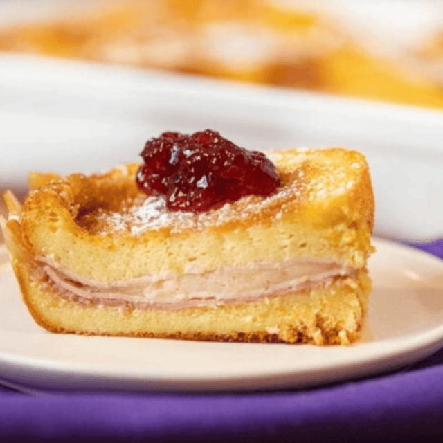 slice of casserole on a white plate topped with jam