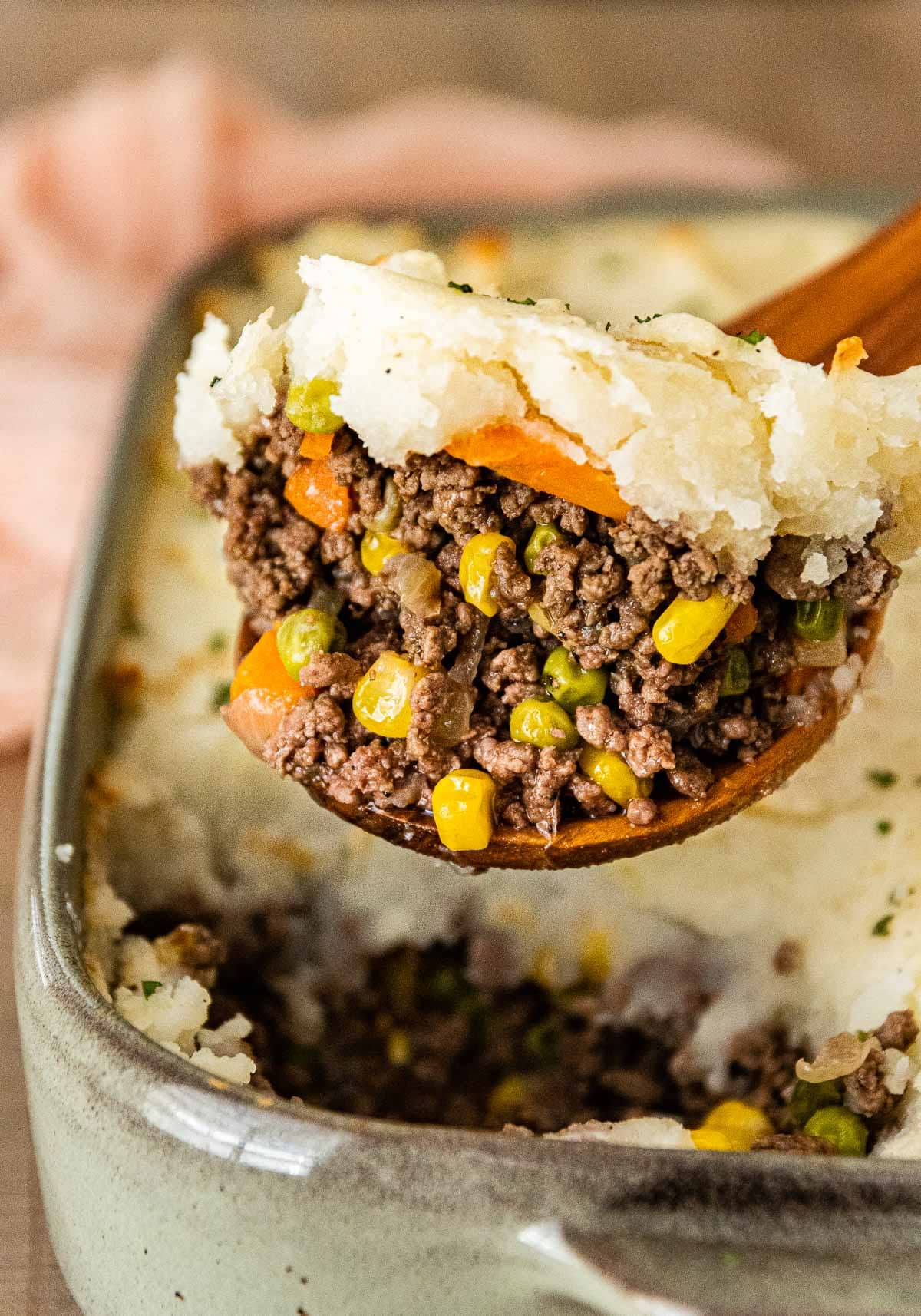 Beef Shepherd's Pie in baking dish with wooden spoon scooping