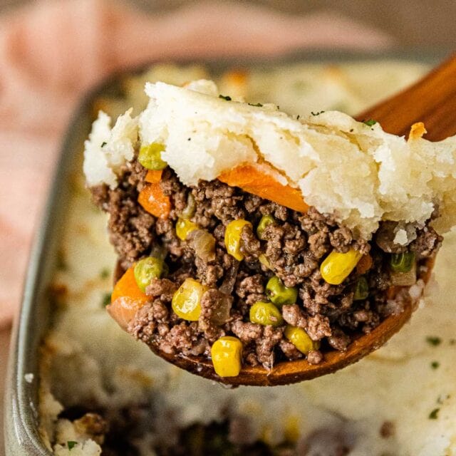 Beef Shepherd's Pie in baking dish with wooden spoon scooping