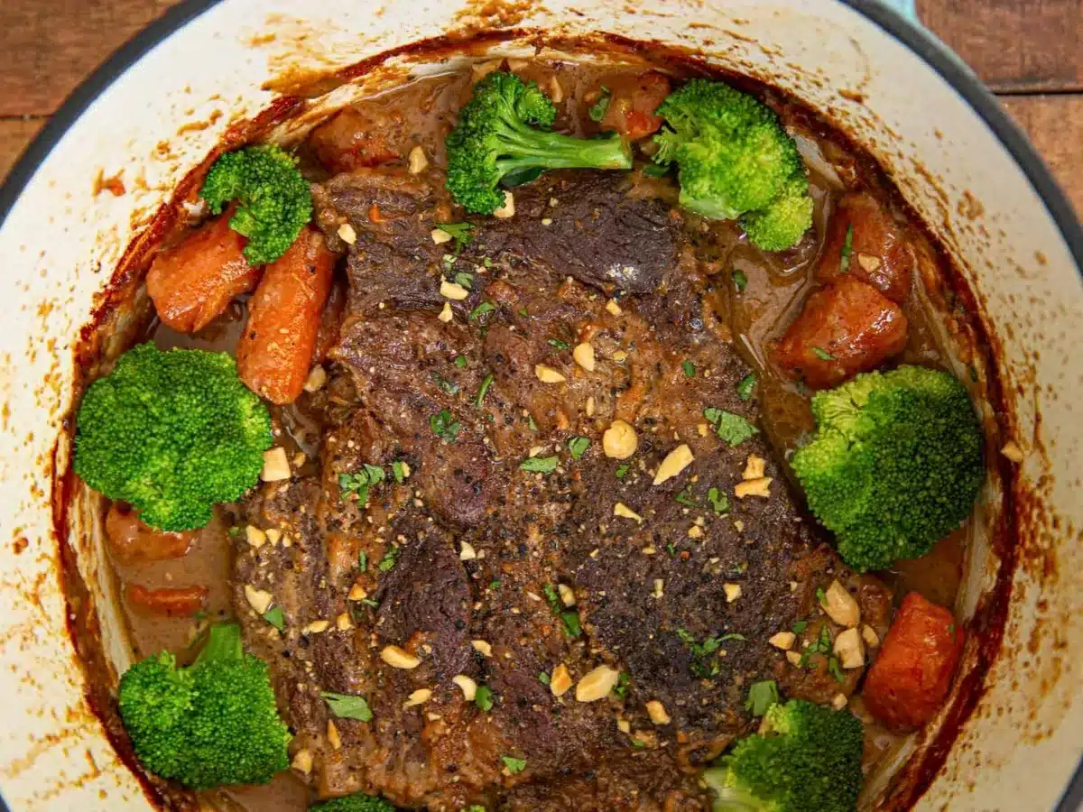 beef covered in sauce with carrots and broccoli in pot