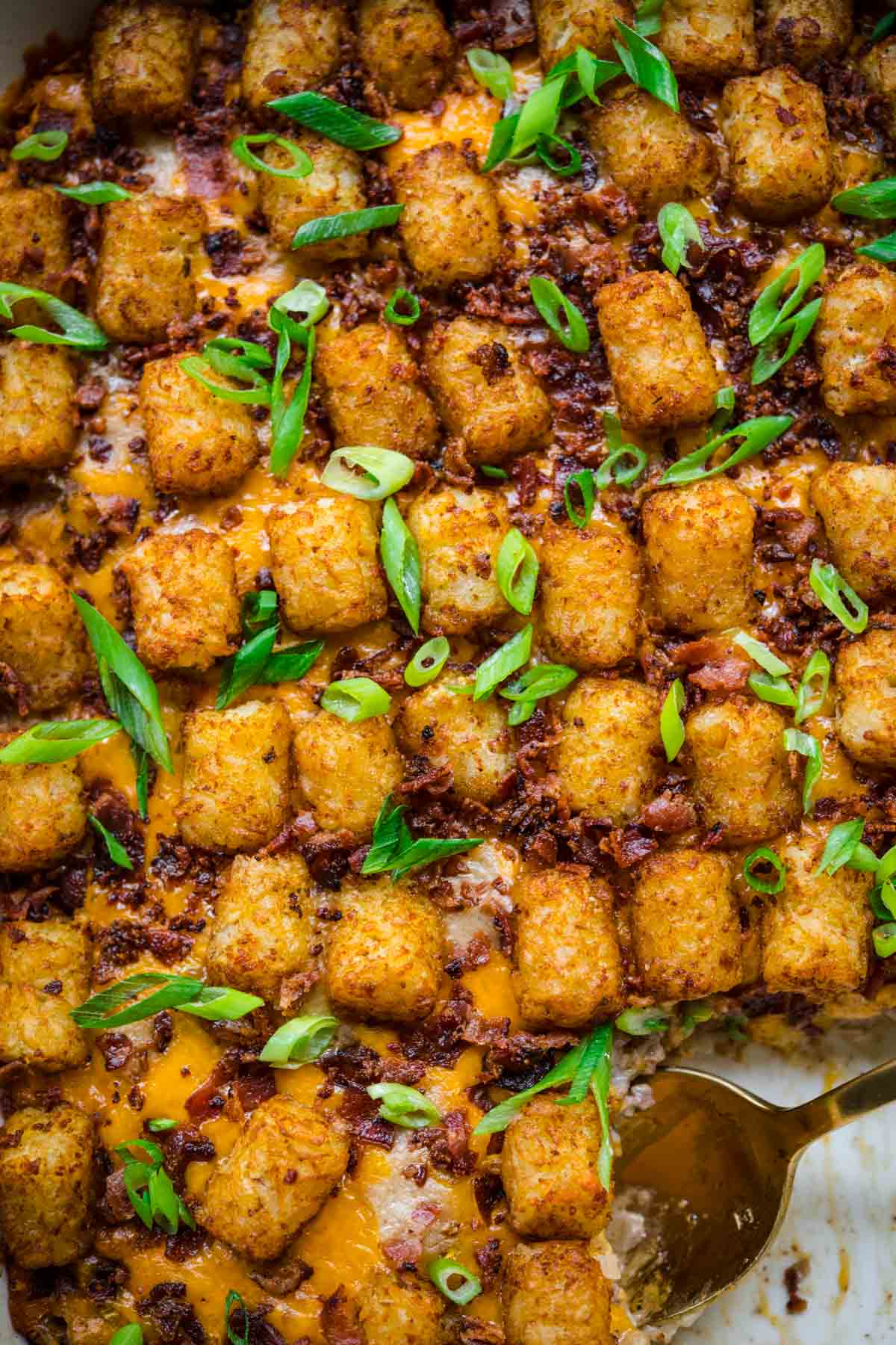 Close up of finished Bacon Cheeseburger Tater Tot Casserole in 9x13 pan with bacon and green onions garnish