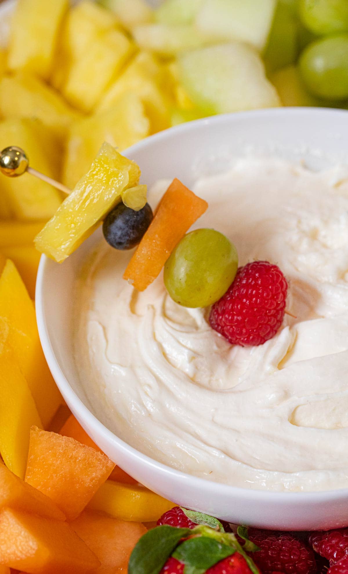 Fruit Dip with rainbow fruit skewer dipped into bowl