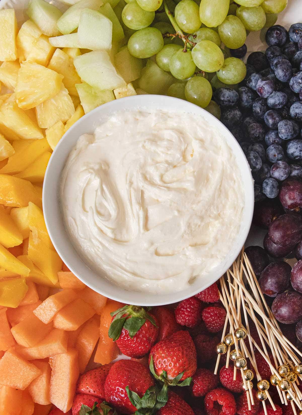 Fruit Dip in bowl in center of serving platter with rainbow fruit