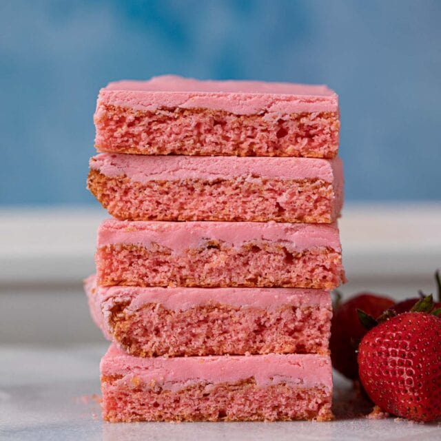 Pink brownies in stack with fresh strawberries
