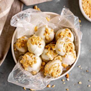 Peanut Butter Snowballs covered in white chocolate and crushed peanuts in a serving bowl