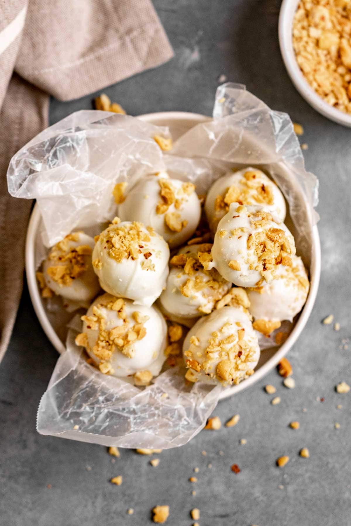 Peanut Butter Snowballs covered in white chocolate and crushed peanuts in a serving bowl
