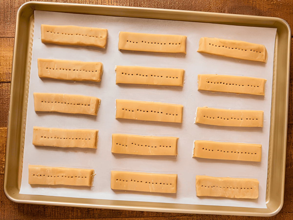 unbaked rectangular cookies with holes in them on a baking sheet