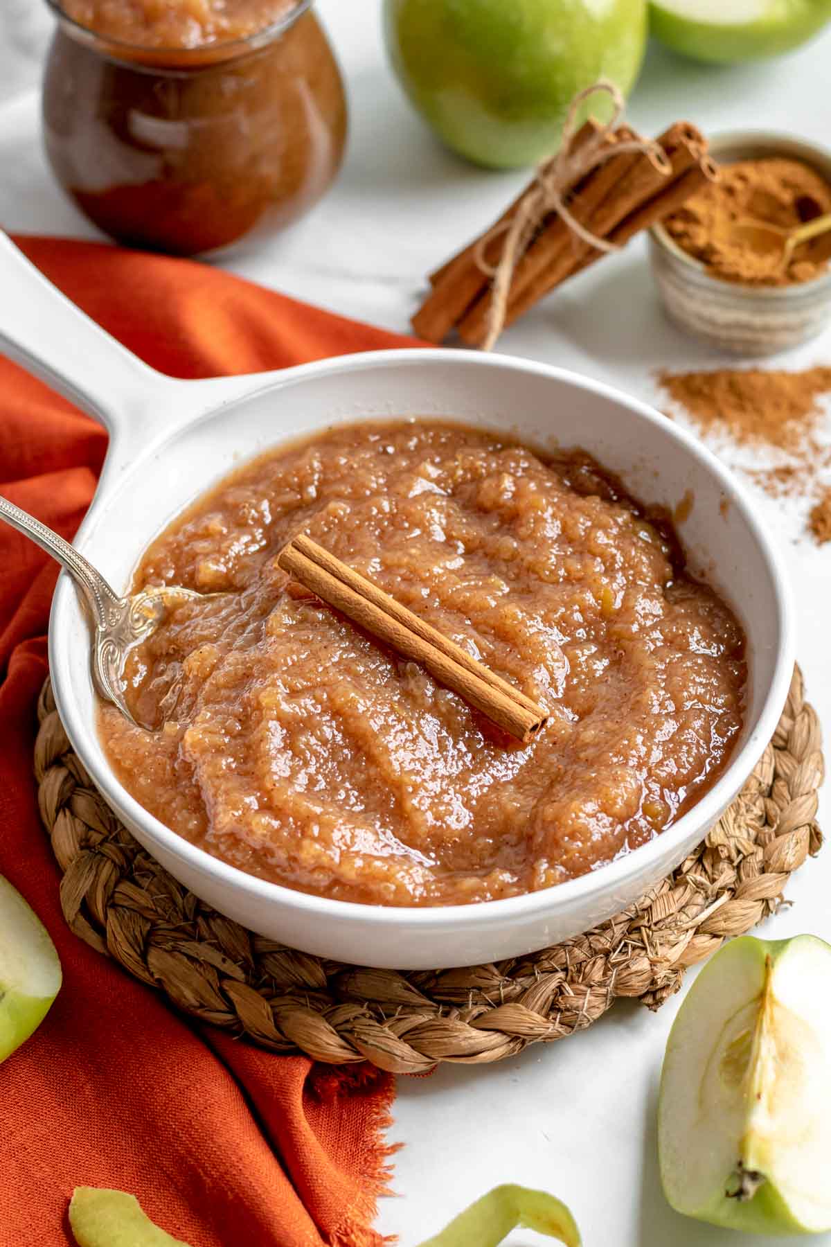 Slow Cooker Applesauce in serving dish with cinnamon stick and spoon