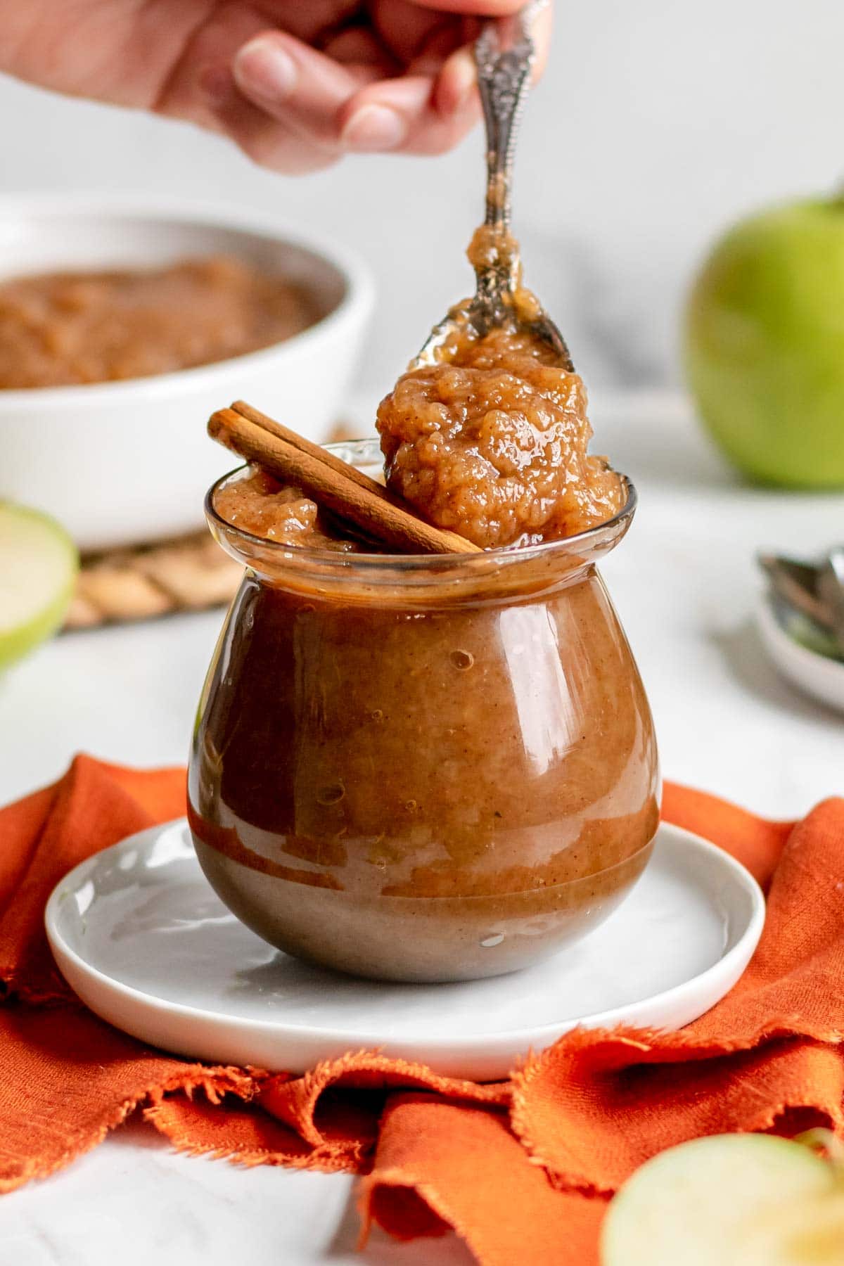 Slow Cooker Applesauce in jar with cinnamon stick and spoon