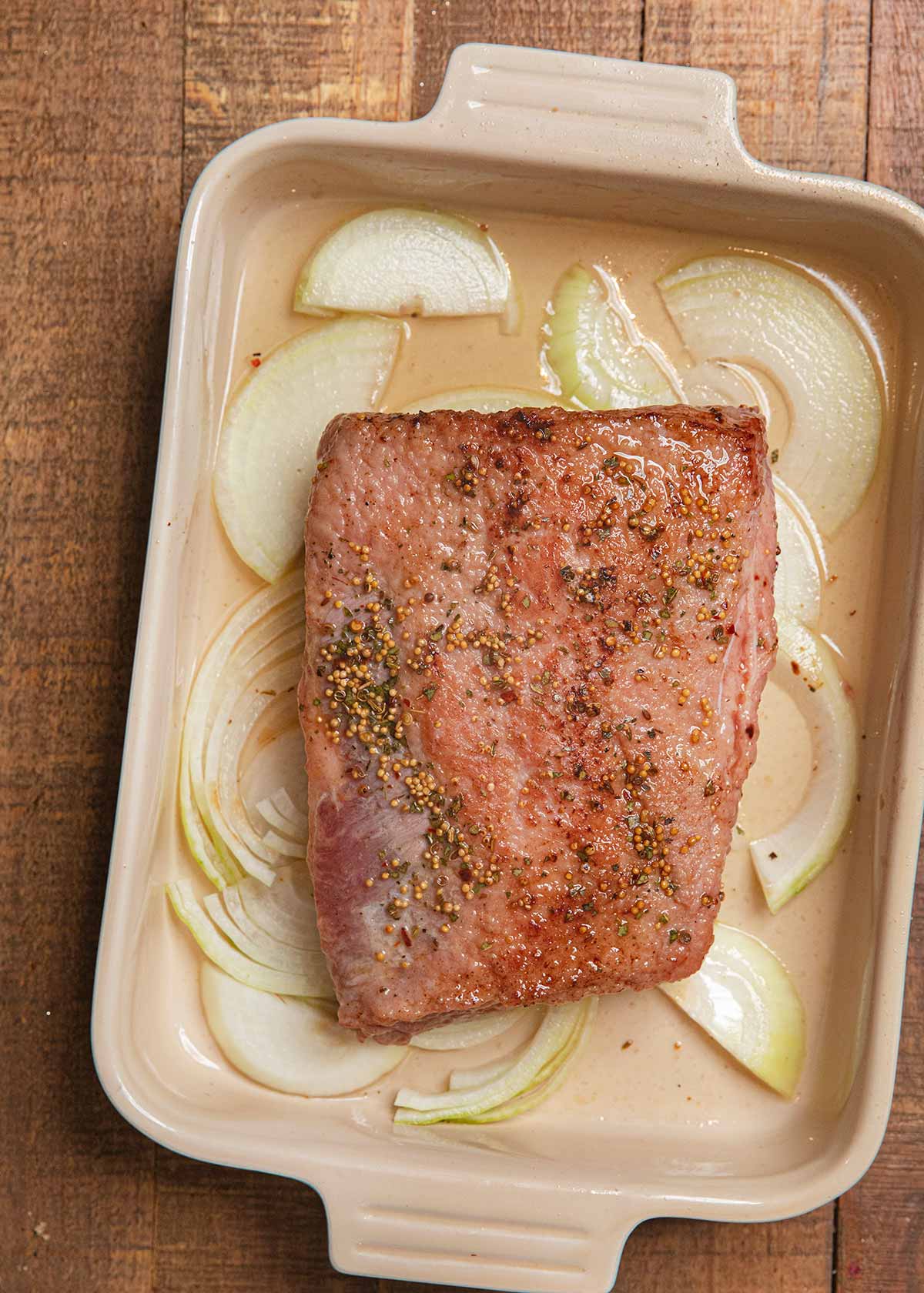 Braised Corned Beef in baking dish with onions before baking
