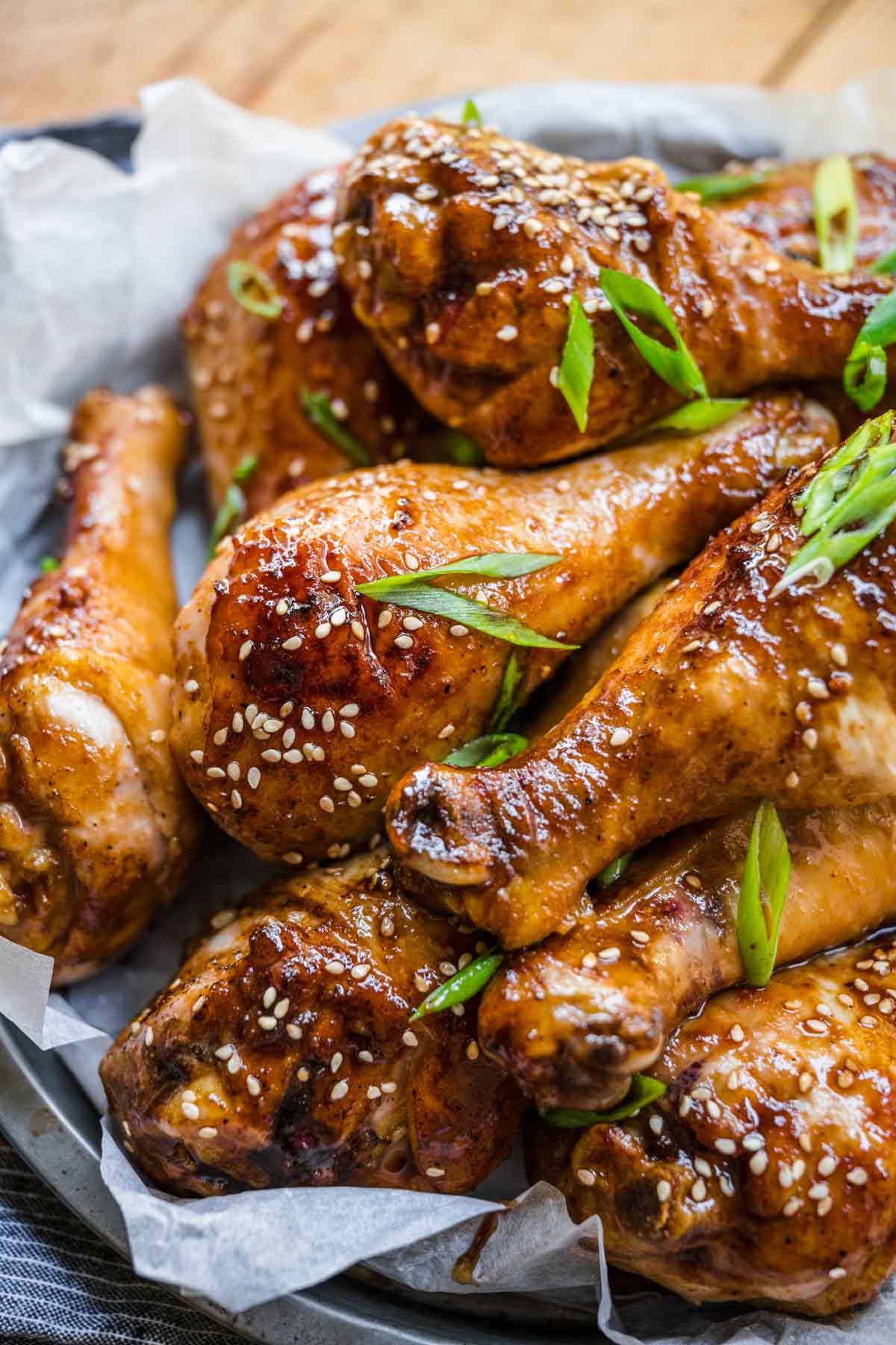 Brown Sugar Garlic Baked Chicken Legs sauce and chicken on serving plate with sliced green onions and sesame seeds