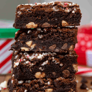 square fudgy cocoa dessert with minty confections on top stacked on one another