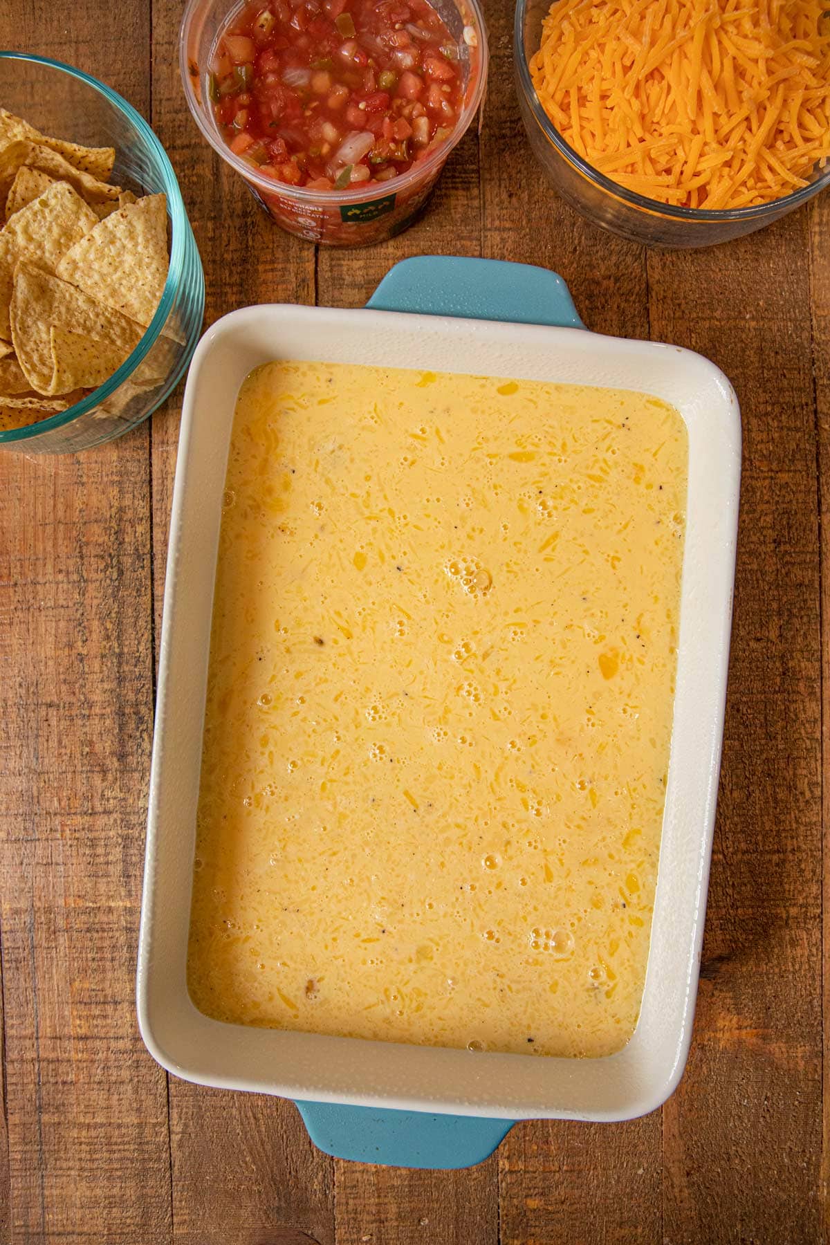 Cheesy Baked Chilaquiles eggs in baking dish with ingredients in bowls