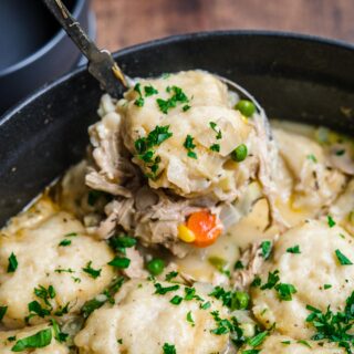 Chicken and Dumplings Soup in pot with parsley garnish and ladle