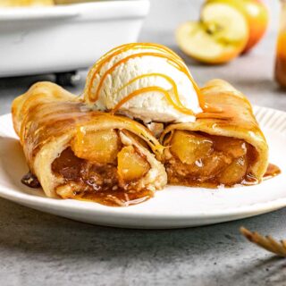 Cinnamon Apple Enchiladas two on plate topped with ice cream and caramel sauce