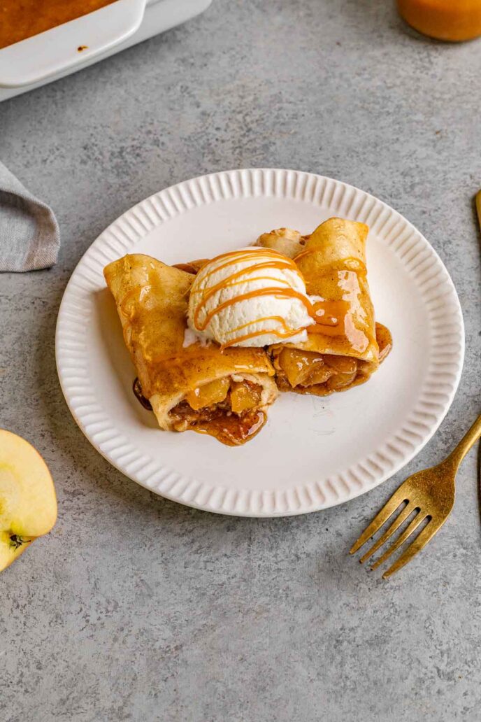 Cinnamon Apple Enchiladas two on plate topped with ice cream and caramel sauce