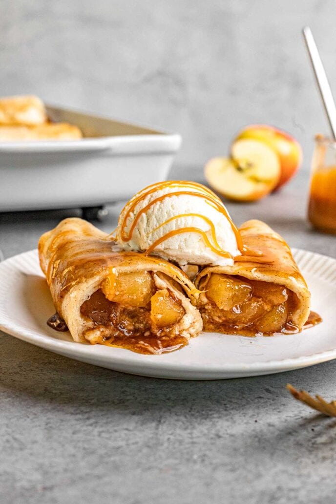 Cinnamon Apple Enchiladas two on plate topped with ice cream and caramel sauce