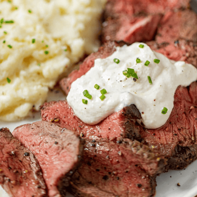 sauce topped on steak with mashed potatoes on the side.