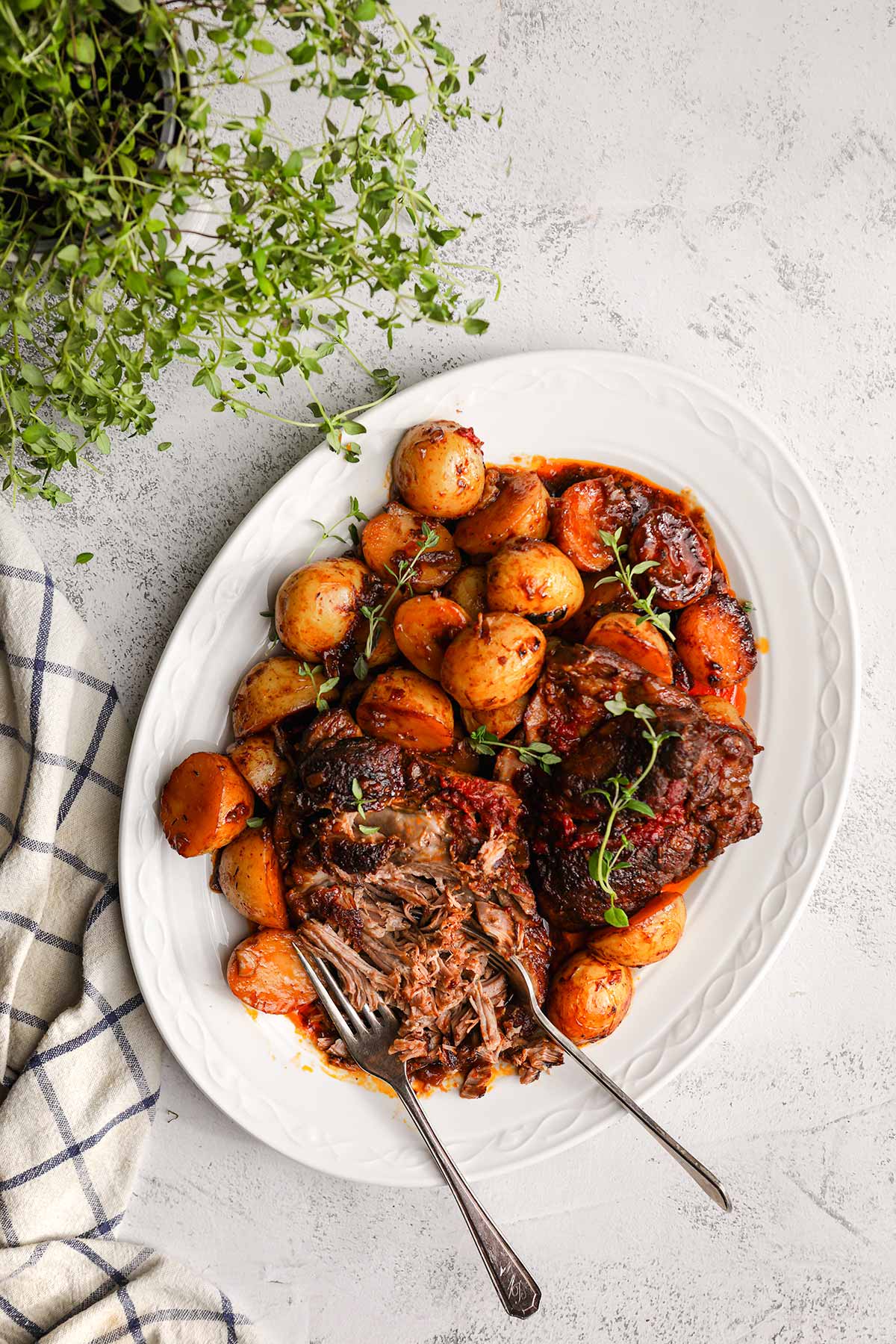 Irish Guinness Roast Lamb with potatoes on serving plate with forks shredding