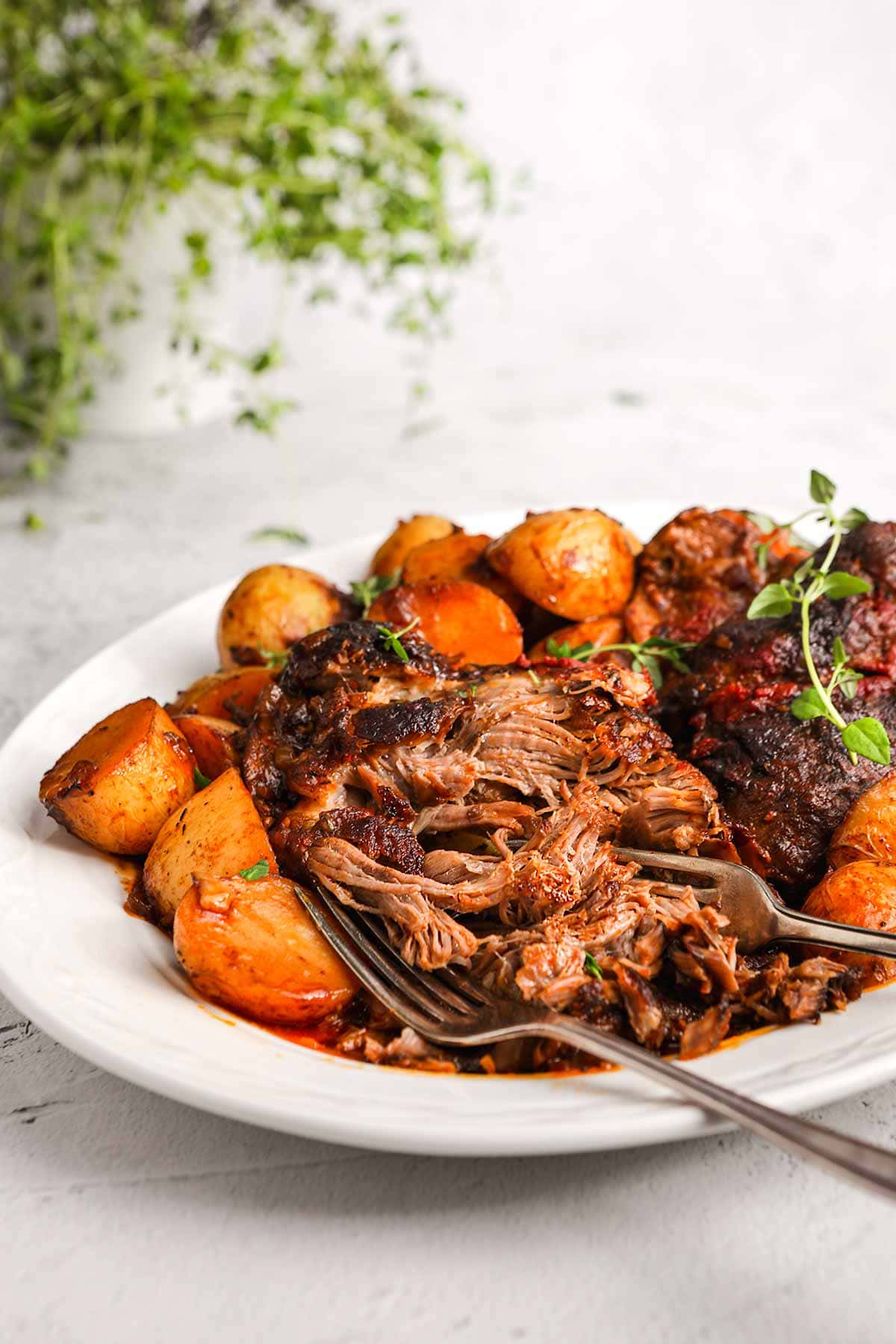 Irish Guinness Roast Lamb with potatoes on serving plate with forks shredding