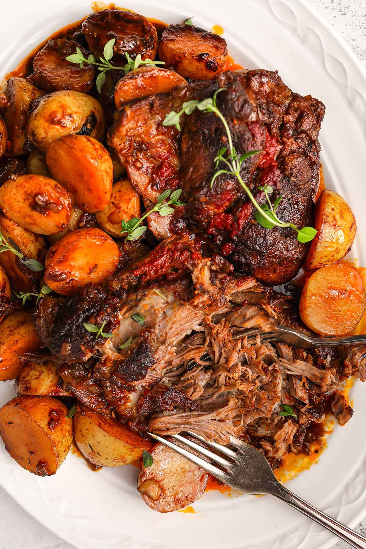 Irish Guinness Roast Lamb with potatoes on serving plate with forks shredding