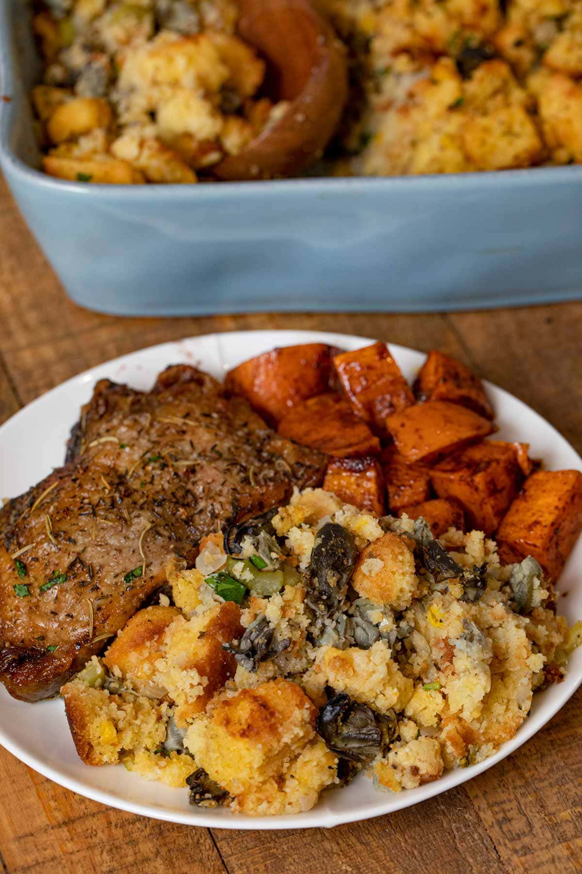 Oyster Cornbread Dressing in baking dish on plate with turkey and sweet potatoes