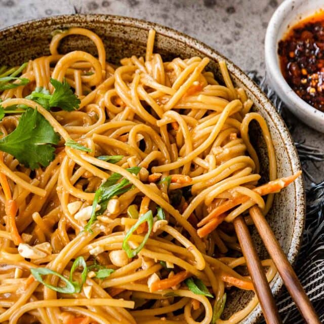 Spicy Peanut Noodles in serving bowls with chop sticks and cilantro lime garnish