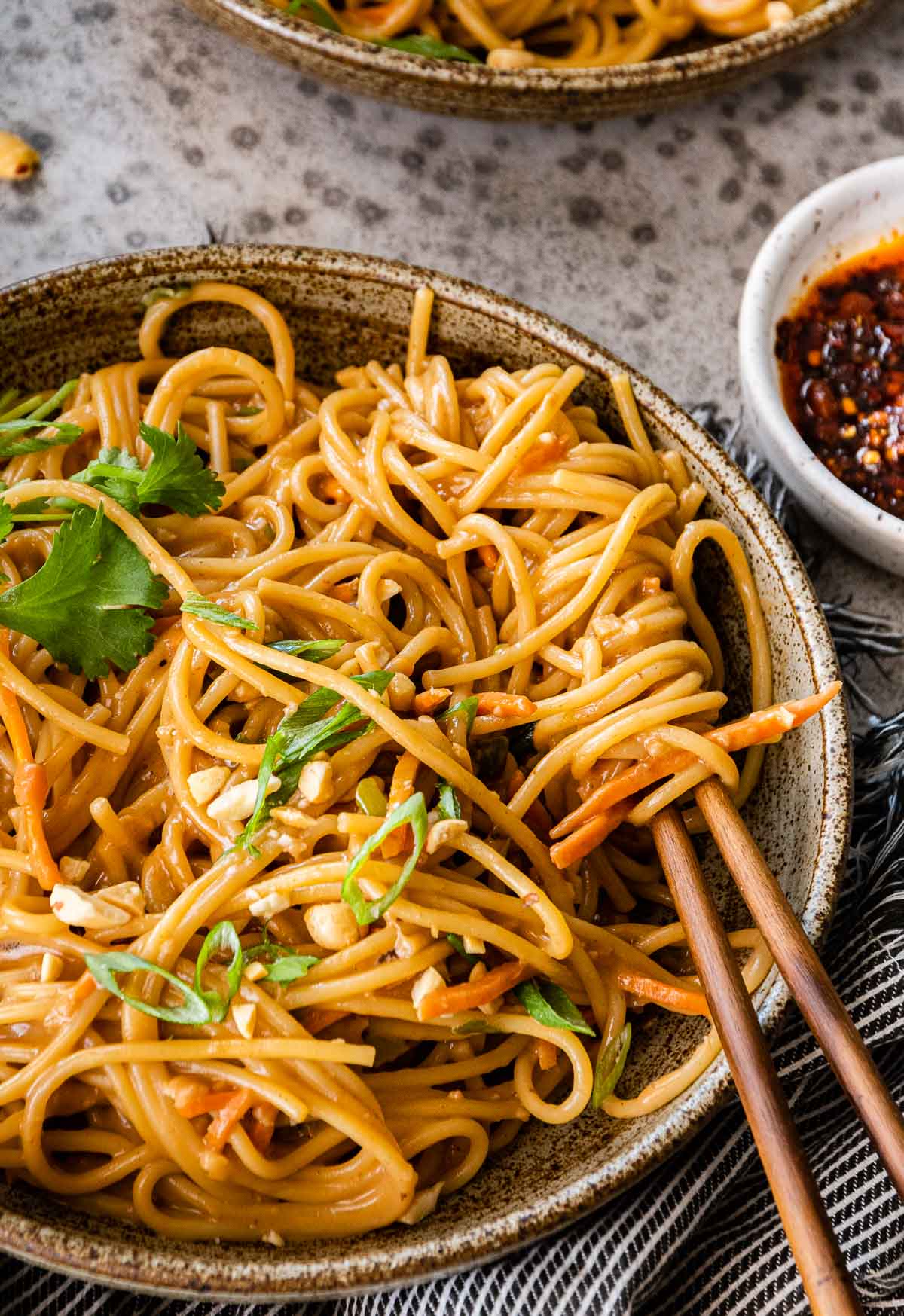 Spicy Peanut Noodles in serving bowls with chop sticks and cilantro lime garnish