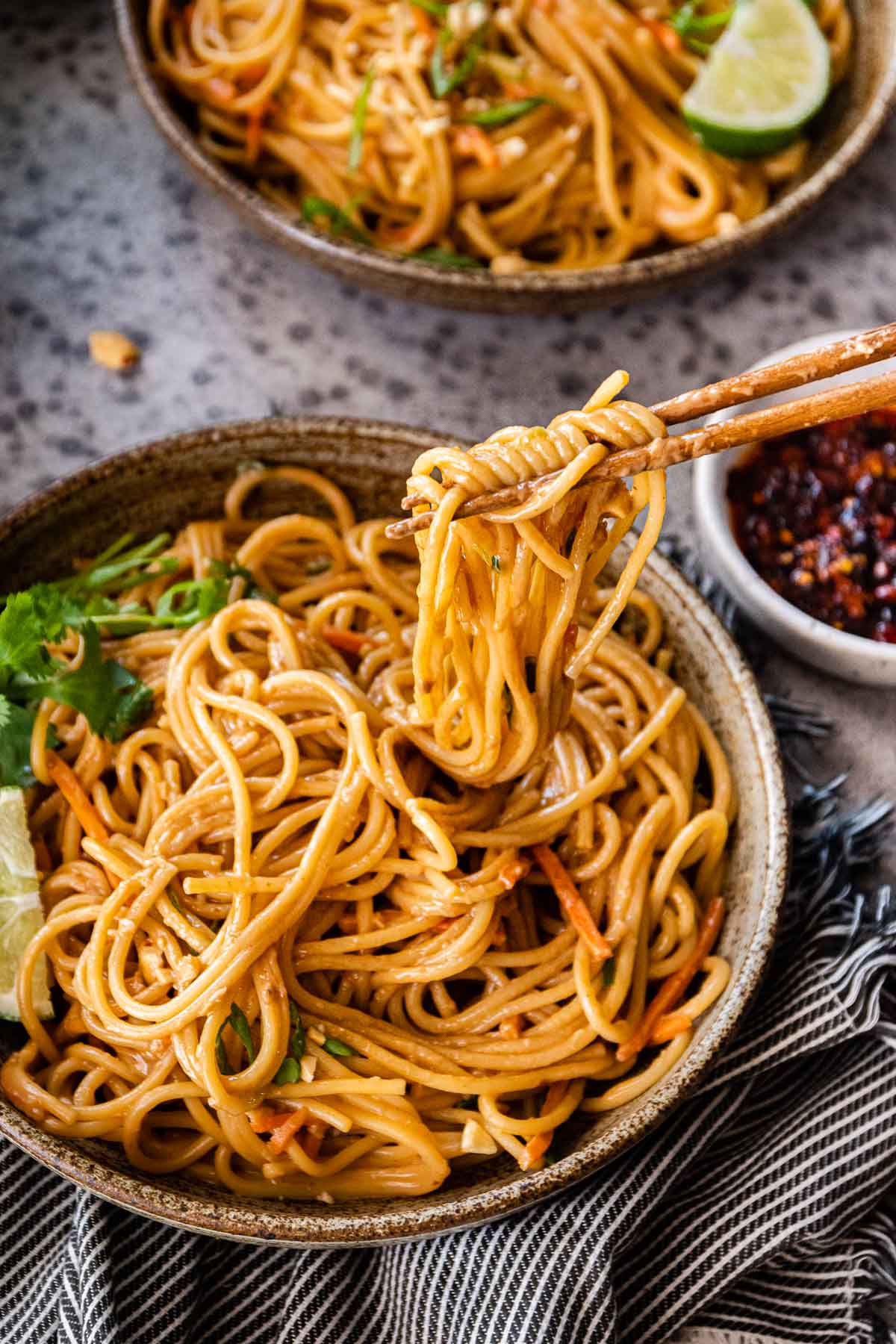 Spicy Peanut Noodles in serving bowls with chop sticks and cilantro lime garnish