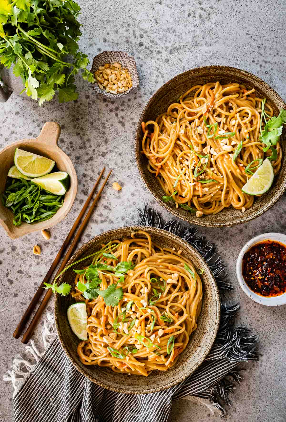 Spicy Peanut Noodles in serving bowls with chop sticks and cilantro lime garnish