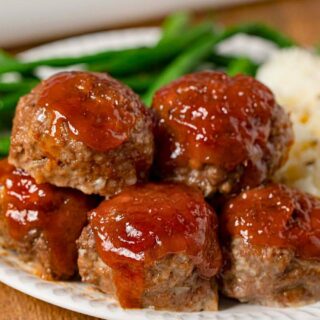 meatballs piled on plate with mashed potatoes and green beans
