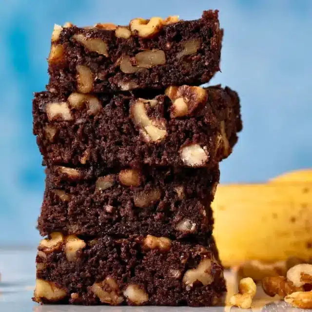 fudgy dessert squares with nuts stacked on top of one another